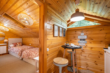 Fototapeta na wymiar Small stylish kitchen and cozy bedroom in wooden house. Village life concept.