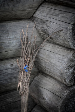 old battered witch's broom on the background of a wooden log house. Traditional Halloween symbol.