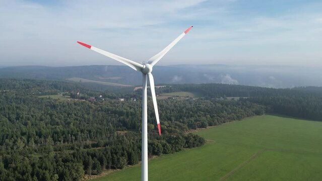 The drone camera slowly approaches the rotating propeller of a wind turbine. Panorama of the Krusne Hory, Czech, Europe