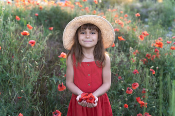 Cute kid holding a poppy flower. Beautiful little girl in poppies flowers in light of sun. Happy...