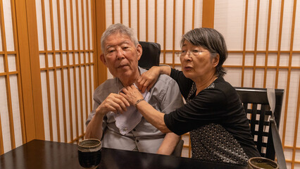 和食屋で外食する高齢者夫婦 前掛けを付け直す妻