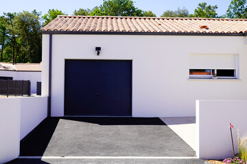 modern white house with black garage door without gate portal of suburb house