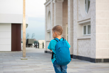 A boy on a scooter along the embankment of the city. Journey. Backpack on the back. The face expresses natural joyful emotions. Not staged photos from life