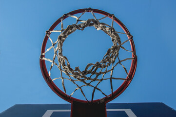 Basketball hoop with a grid on a blue sky background with a copy space background. Bottom view. Sports team game basketball, streetball.