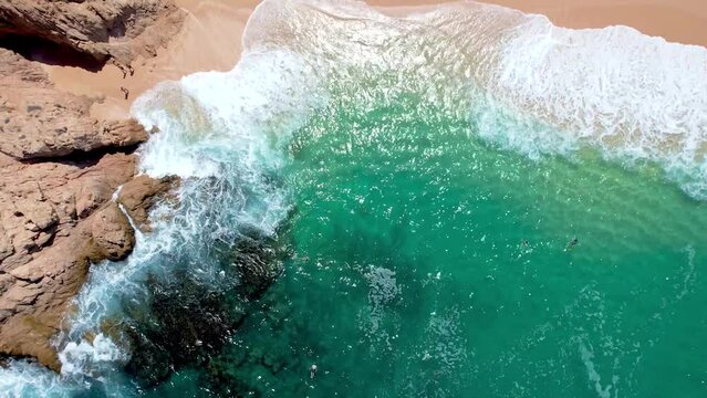 clear turquoise water. aerial drone headshot of waves crashing on sea cliffs in Cabo San Lucas Mexico. waves crashing into rocky shoreline. 4K videos.