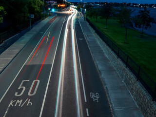 Night scene in a city with car trail lights and 50 kilometer and hour speed limit. Safety measures. Dark and moody feel. Red and white color of traffic in urban area.