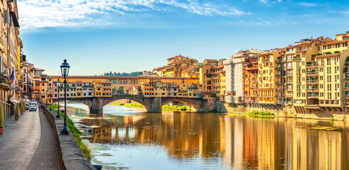 Panorama of beautiful medieval bridge Ponte Vecchio over Arno River, Florence, Italy. Architecture and landmark of Florence. Travel concept background. - obrazy, fototapety, plakaty