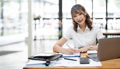 Cheerful young female businesswoman or student smiling and working on computer laptop at office.