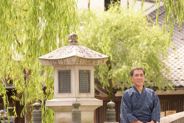 城崎温泉の柳通りを浴衣を着て散策する笑顔のシニア男性
