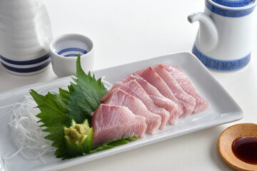 Raw Yellowtail fish or Hamachi sashimi on white plate with soy sauce and Japanese Sake-Japanese food