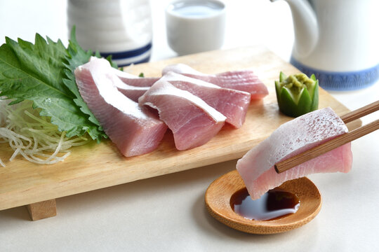Eating Raw Yellowtail fish or Hamachi sashimi with chopsticks on soy sauce-Japanese food