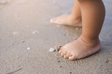 Baby learning to walk on the beach.Close-up at baby's feet.