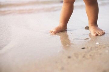 Baby learning to walk on the beach.Close-up at baby's feet.