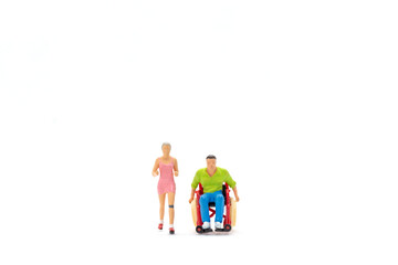 Miniature people Cheerful woman with young disabled man in wheelchair running on white background
