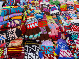 Fototapeta na wymiar Many colorful knitted clothing in the form of mittens, gloves. Lots of mittens, gloves for cold seasons. Bright mittens and gloves are piled up as a texture background. Top view
