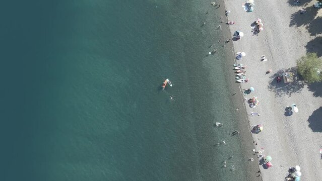 top down view of people bathing in the Ranco lake in chile in the blue and teal waters with people paddleboarding