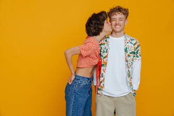 Young beautiful short-haired woman kissing her smiling curly boyfriend