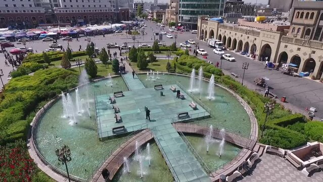 An aerial shot of the city of Erbil showing the ancient Erbil Citadel and the garden opposite the castle with water fountains and the popular market