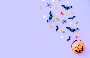 composition on the theme of the holiday halloween bucket pumpkins sweets bats spiders on a purple...