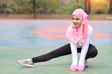 Athletic young beauty asian woman in muslim sportswear stretching and lifting dumbbells public...