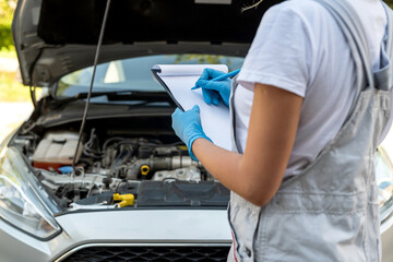 beautiful female mechanic is working on a car breakdown at a car repair shop.