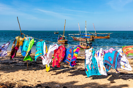 Sansibar, Dhow-Boote am Strand im Dorf Fumba auf Sansibar in Tansania. Im Vordergrund bunte T&uuml;cher.