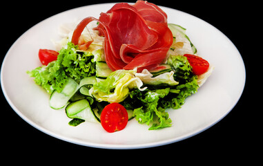 Salad with jamon and vegetables on a plate isolated. Meat food.
