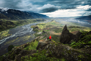 Hiker man in red jacket standing on top of Valahnukur surrounded by volcanic mountain and Krossa...