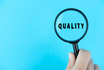 Focused or searching for quality. Word under magnifying glass.  Financial terms. Manager (businessman, coach, leadership) is focused on quality in business (total quality management concept). 
