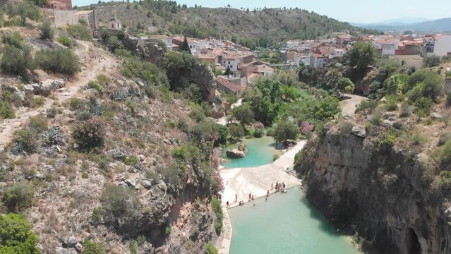 People swim in natural pools formed in river at Bolbaite, Spain seen from drone.