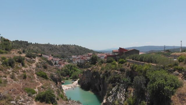 Wide aerial view of small Spanish village on cliffs above river. Dolly right.
