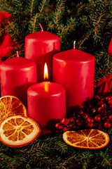 First burning Red advent candles in advent wreath decoration on wooden dark background. tradition...