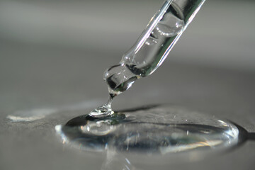 Pipette with spilled cosmetic oil or serum on a gray background.
