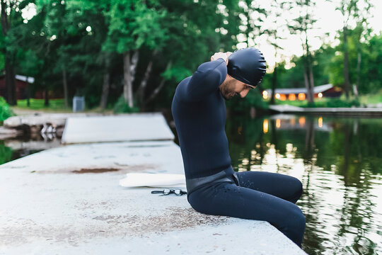 Man adjusting swimming cap sitting by lake - Powered by Adobe