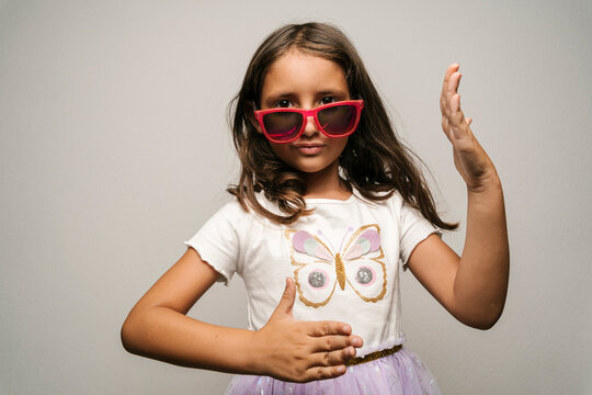 Girl Wearing Sunglasses Doing Robot Dance Against Gray Background
