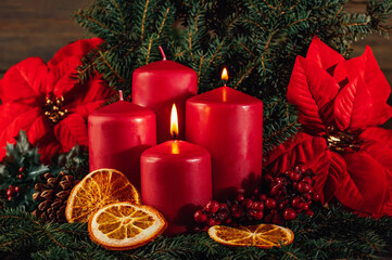 Two burning Red advent candles in advent wreath decoration on wooden dark background. tradition in...