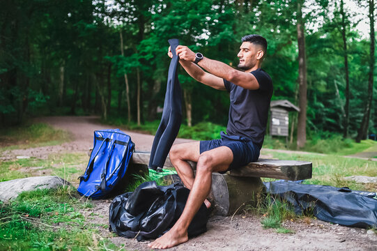 Man looking at neoprene suit sitting on bench - Powered by Adobe