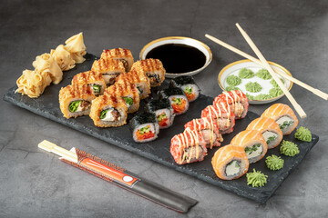 Sushi set of various products on a black stone plate. Blur background and selective focus