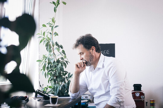 Thoughtful businessman looking at tablet PC at office