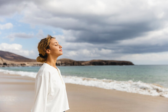 Woman standing with eyes closed at beach