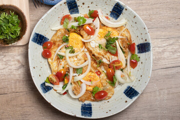 Spicy fried egg salad with vegetables, tomatoes, onions