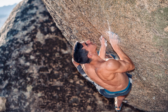 Young muscular athlete doing rock climbing