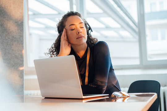 Tired customer service representative sitting with eyes closed at desk in office