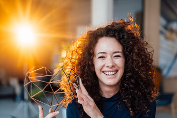 Happy woman with curly hair holding heart shape model