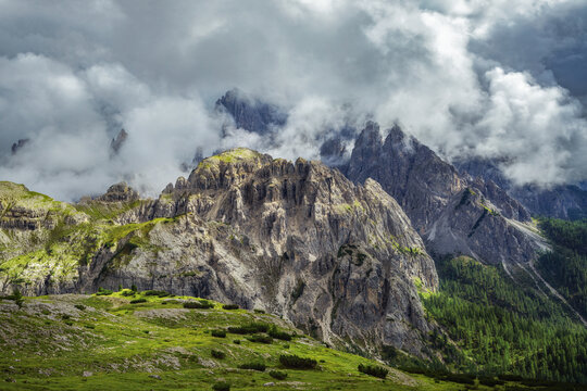 Beautiful mountain landscape with rocks, green lawn, thunder clouds and fog in cloudy weather. Tre Cime park in Dolomites, Italy. Italian alps