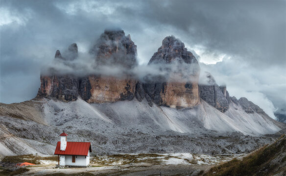 Tre Cime park in Dolomites, Italy. Mystical beautiful landscape with rocky mountains and beautiful church at dusk, Italian alps