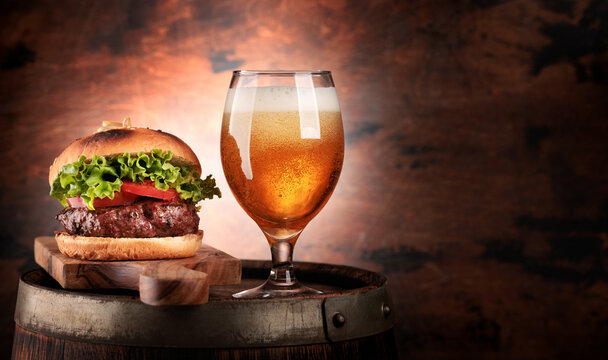 Draft beer glass and hamburger on wooden barrel