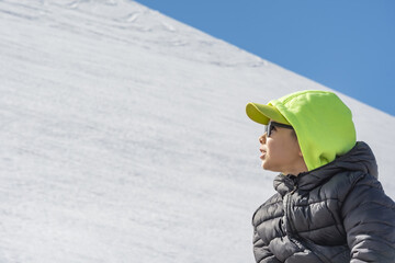 A boy sits on an observation deck against the backdrop of the Caucasus Mountains
