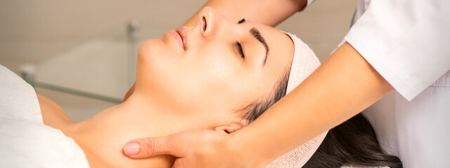 Facial massage. Young caucasian woman getting a massage on her neck in a beauty clinic