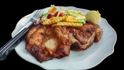 Isolated chicken steak with salad on a white plate on black background